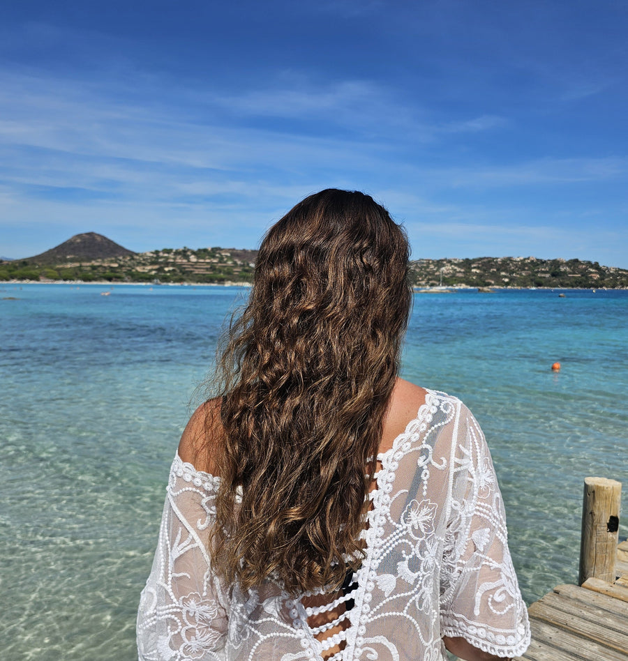 Long wavy hair with sun kissed highlights on a beach dock, showing healthy texture after summer sun and saltwater exposure.